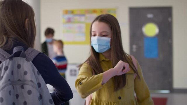 Video of girls in protective masks having an elbow greeting. Shot with RED helium camera in 8K.