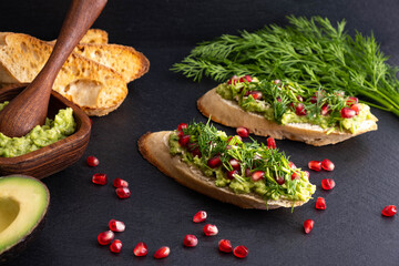 delicious avocado snack, sprinkled with ripe pomegranate seeds, sesame seeds and fragrant fresh dill