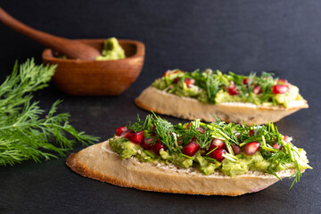 a delicious and healthy snack - avocado, sprinkled with ripe pomegranate seeds, sesame seeds and fragrant fresh dill
