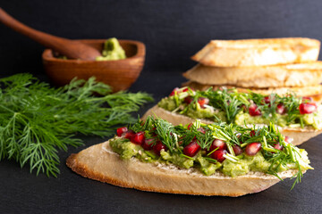 snack - avocado, sprinkled with ripe pomegranate seeds, sesame seeds and fragrant fresh dill