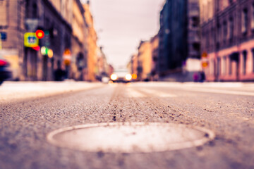 Snowy winter in the big city, the car is a red traffic light. Close up view of a hatch at the level of the asphalt