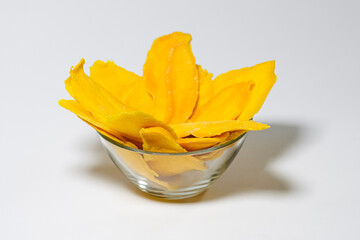 Naklejka na ściany i meble Dried mango slices in glass bowl isolated on white background.