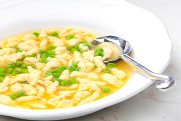 chicken bouillon with homemade dumplings and green peas