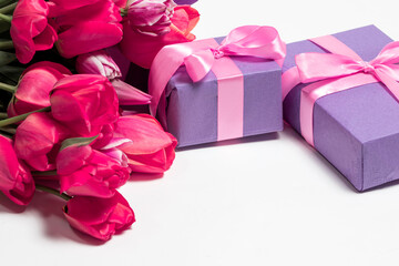 Tulips and lilac gift boxes with a place for text on white background. Holiday vertical card for inscription.