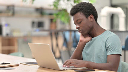 Tired Young African Man with Laptop having Neck Pain