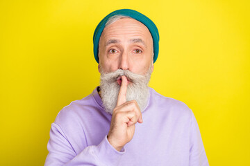 Photo of strict cute mature man dressed purple pullover headwear arm lips ask shut up isolated yellow color background