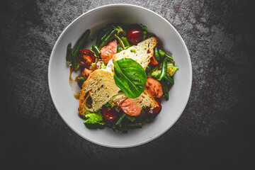 Green Bean Salad with Boiled Eggs, Salmon, Tomatoes and Arugula in a bowl on Dark grey black slate background