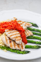 grilled poultry meat with baked red pepper sauce and green asparagus