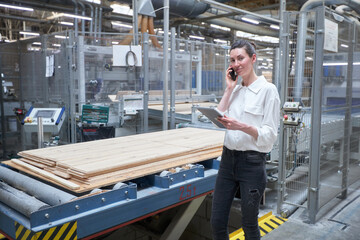 Business woman worker in the carpentry factory using tablet pc. Carpentry factory. Factory for the production of parquet board