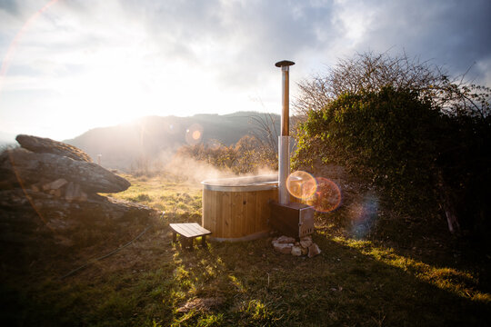 Amazing romantic location for steaming hot tub warmed by fire wood. Glamping staycaion vacation destination. Steam come out of outdoors hot tub at spa resort in woods nature