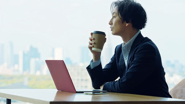 コーヒーを飲みながらパソコンを見るビジネスマン