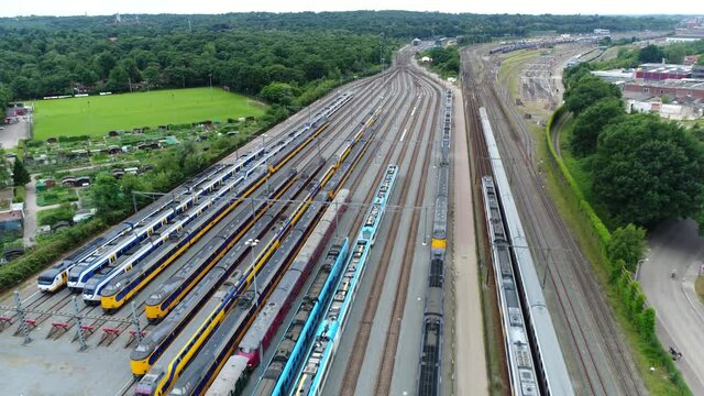 Aerial bird view of trains parked at a service station that run along a railroad track to transport passengers showing lots of tracks straight next to each other and the railway cars 4k quality