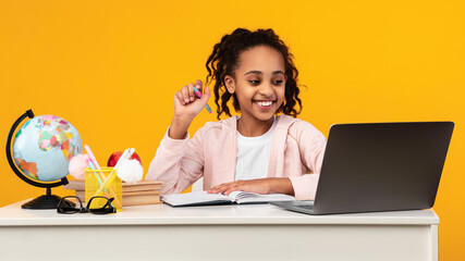Portrait of smiling black girl sitting at table and writing