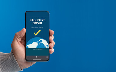 phone in hand with covid passport on screen, with blue background,