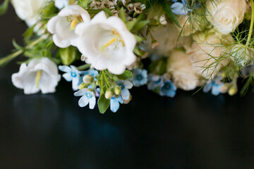 Close up of white, blue and green flower bouquet placed on a wooden table