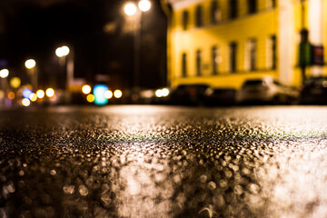 Rainy night in the big city, the empty street. Close up view from the asphalt level