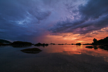 Beautiful landscape with colorful sunset on the sea rock beach.