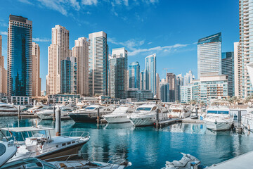 Small yacht and motor boats parking at the port near Dubai Marina Mall with row of high skyscrapers residential buildings and hotels - obrazy, fototapety, plakaty