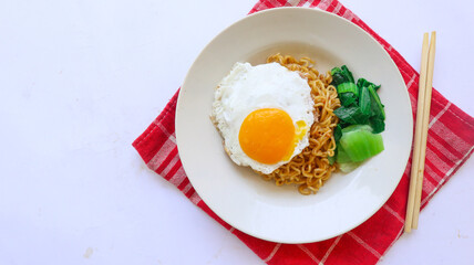 instant noodles served with egg fried and mustard greens on plate. instant fried noodle indomie
