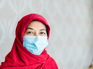Fototapeta premium 50-60 years old senior woman muslim smile isolated background.Portrait of old muslim woman wearing hijab at home looking at camera.Indian muslim woman with mask. mother day.Health medical mental.