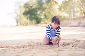 7 years old asian girl play sculpture white sand on the sea beach.Vacation and relax.Playful active kid on beach in summer vacation and child development.Asian kid girl play in sand beach in thailand.