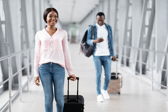 Travel Insurance Concept. Cheerful Black People Walking With Luggages In Airport Terminal