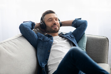 Joyful middle-aged man in headphones listening to music