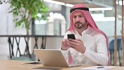 Professional Arab Businessman using Smartphone and Laptop 
