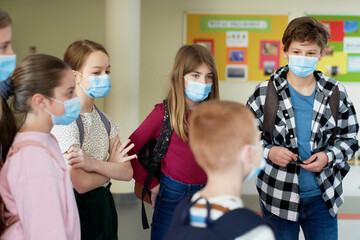 School children standing in the hallway wearing a protective mask