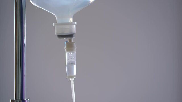 Close up IV fluid. Saline solution on blurred gray background in hospital. 
