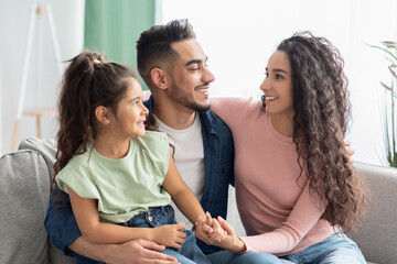 Family First. Happy Arab Mom, Dad And Daughter Embracing On Couch
