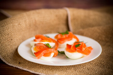 halves of boiled eggs with pieces of salted salmon