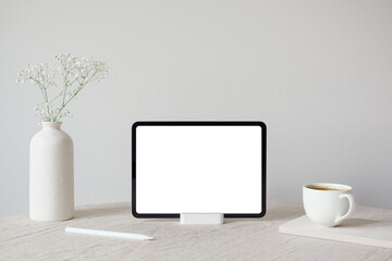 Tablet screen mockup, vase of flowers and coffee cup. White wall on background. Cozy, hygge, nordic...