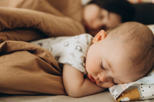 selective focus, noise effect: portrait of a baby who fell asleep during the day on a bed next to his mother