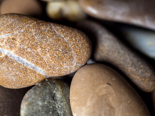 Multi-colored wet pebbles on the shore close-up. Various shapes of stones. Unusual stones. Macrocosm. Pebble background. Shore. Beach. Pebble texture