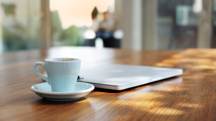 Workplace with white laptop, notebook and coffee on wooden desk .Coffee cups ,work desk has a laptop and a coffee cup.