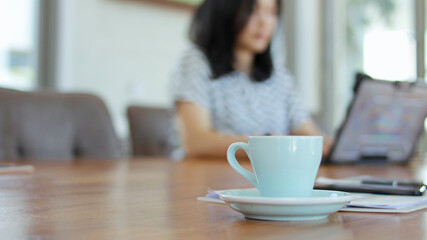 Coffee cups placed on wooden tables at the coffee shop have a blurred background.