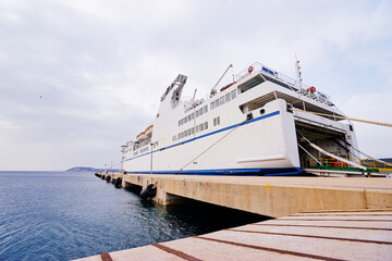 Naklejka premium Ferryboat loading or unloading by a port pier. Concept of transportation and traveling.
