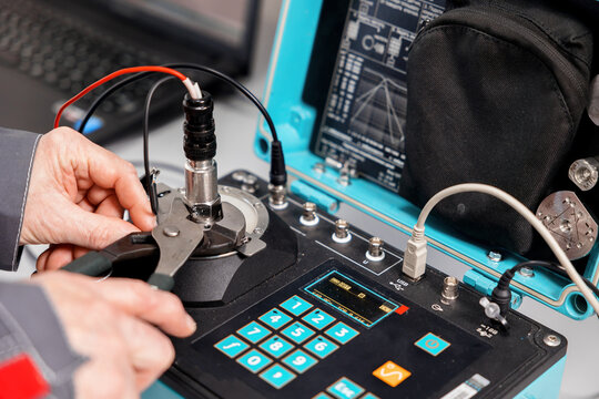 A specialist in the laboratory of metrology and standardization checks the resistance of the sensors to vibrations and shocks on a special test bench. Measuring instruments and standards.