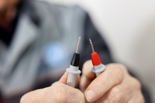 Electrical test leads in the hands of an electrician engineer. Working equipment of the specialist of the laboratory of metrology and standardization. Measuring instruments digital multimeter.