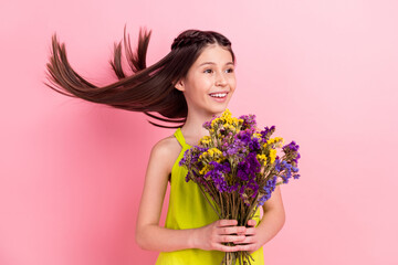Obraz na płótnie Canvas Photo of charming sweet schoolgirl dressed yellow outfit holding wildflowers bouquet looking empty space isolated color background