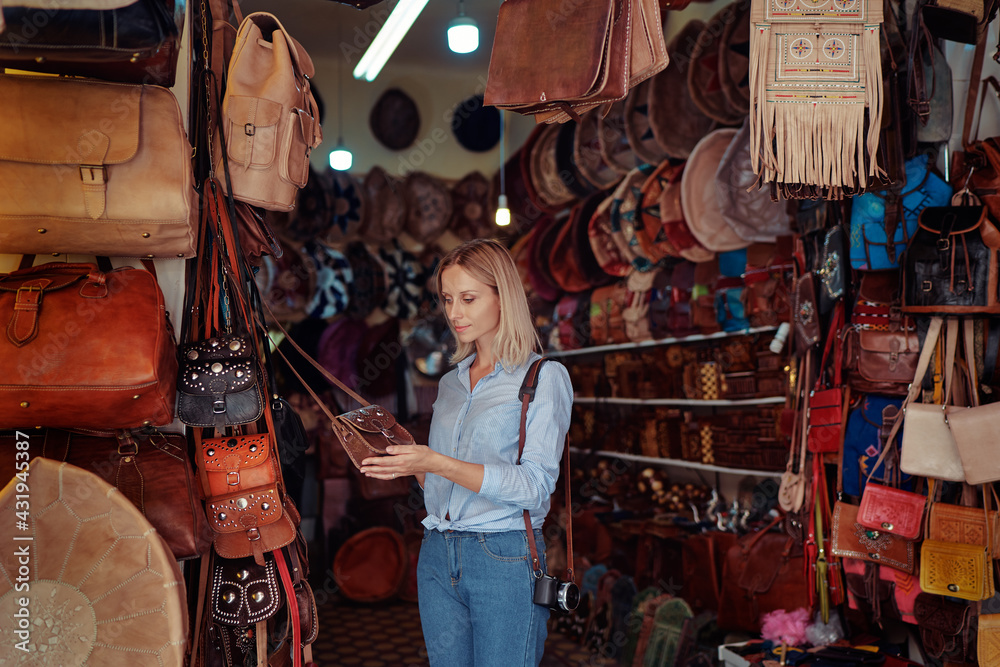 Wall mural Travel and shopping. Young traveling woman with choose presents in bag shop in Morocco.