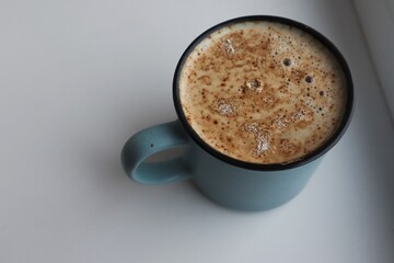 Cappuccino in a gray and blue mug on a white background