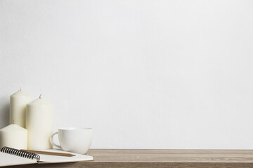 White candles with coffee cup on table with white wall.
