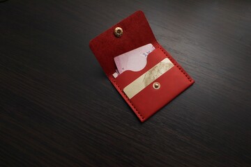 Leather red purse with money and a bank card. Wallet on a dark background