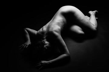 Artistic black and white picture of a nude woman laying on the floor