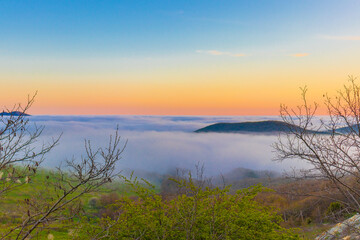 Mountain range with visible silhouettes through the morning colorful fog.