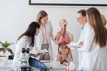 Professor with students analyzing anatomy model in class