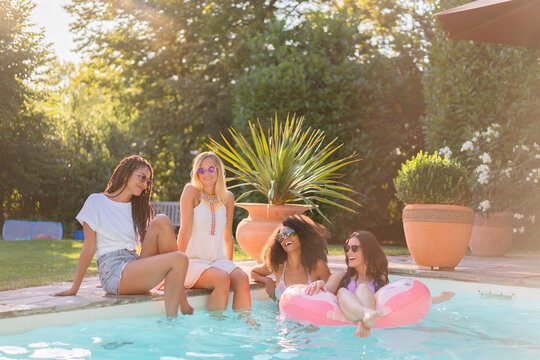 Cheerful female friends having fun in swimming pool during sunny day