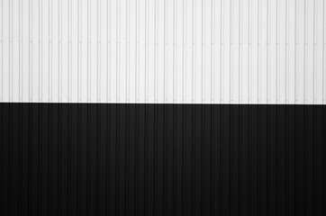 Black and white corrugated iron sheet used as a facade of a warehouse or factory. Texture of a seamless corrugated zinc sheet metal aluminum facade. Architecture. Metal texture.